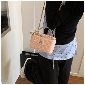 Detail van roze gewatteerde vanity bag met parelhanger en kettingriem op model