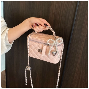 Detail van roze gewatteerde mini box tas met parelstrik en zilveren hart hanger