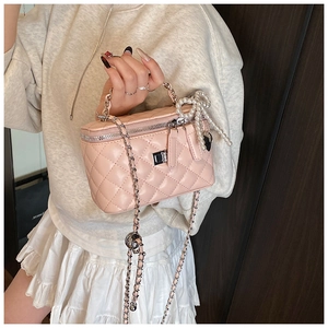 Detail van roze gewatteerde vanity bag met parelmoeren strik en kettingriem