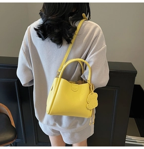 Detail of yellow lychee pattern leather bucket bag with dog charm and thin shoulder strap