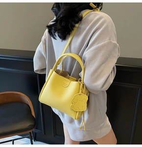 Detail of yellow lychee grain tote bag featuring fashion text and cute dog charm accent