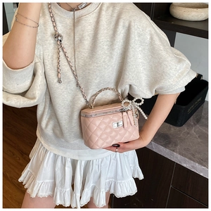 Roze gewatteerde crossbodytas met parelmoer strik en leren ketting op het model