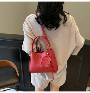 Close-up of red lychee grain leather handbag with puppy charm and embossed logo detail