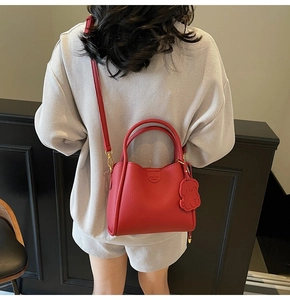 Detail of red pebbled leather handbag with adjustable strap and cute puppy charm