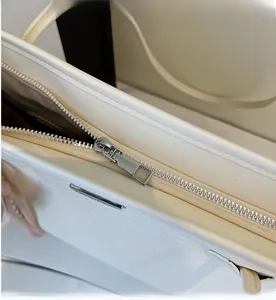Close-up of the smooth silver metal zipper on a white woven minimalist tote bag