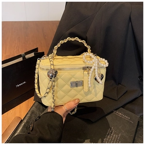 Detail van gewatteerde box-tas met parelstrik en gouden metalen ketting