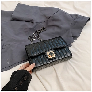 Detail of black quilted chain bag with gold floral clasp and honeycomb pattern