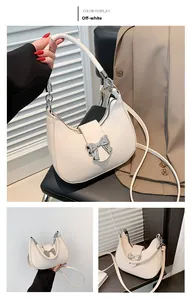 Détail du sac demi-lune blanc cassé avec nœud argenté et texture en cuir lisse