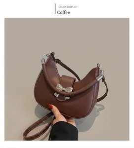 Détail du sac demi-lune marron avec nœud métallique argenté et finition en cuir lisse