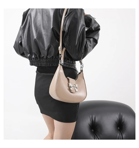 Détail du sac hobo beige avec un nœud métallique argenté et une bandoulière réglable