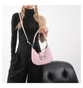 Vue détaillée du sac demi-lune rose avec boucle nœud argenté et cuir mat élégant