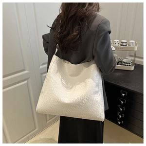 Femme portant un grand sac cabas blanc tissé à l'épaule dans un intérieur moderne