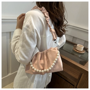 Detailed close-up of pink pleated cloud bag featuring faux pearl chain and fabric strap