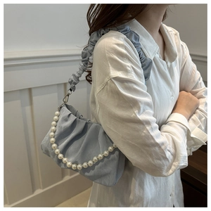 Detail of light blue pleated bag with white pearl chain and ruffled shoulder strap