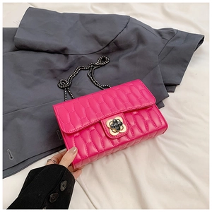 Detail of rose red quilted bag showing flower twist lock and black metal chain strap