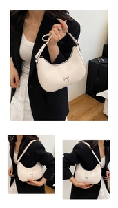 Detail view of cream crescent hobo bag featuring a silver metal bow and adjustable strap