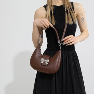 Sac sous le bras demi-lune marron foncé avec boucle nœud argenté sur modèle