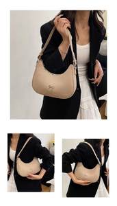 Chic beige crescent underarm bag with silver bow accent shown on model with shoulder strap