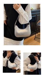 Detail view of a silver metallic hobo bag featuring a bow decoration and adjustable strap