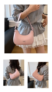 Detail of light pink hobo bag with silver bow charm and adjustable shoulder strap