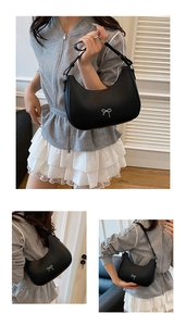 Detail of black crescent shoulder bag with silver bow accent and leather texture