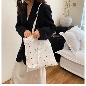 Gros plan sur un sac cabas en toile blanche avec motifs floraux noirs et étiquette