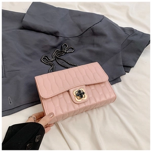 Detail of pink quilted crossbody bag featuring a golden flower clasp and metal chain