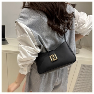 Model wearing black matte leather baguette bag with golden buckle and chain strap