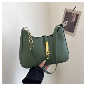 Détail d'un sac à bandoulière vert foncé avec chaîne dorée et boucle métallique