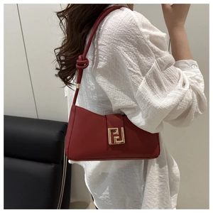 Detail of red crescent shoulder bag with golden buckle and knotted strap on model