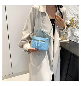 Detail of light blue quilted mini bucket bag with gold chain strap on light coat