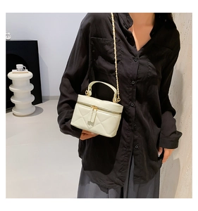 Quilted cream crossbody bag detail with gold chain strap shown on model in black outfit