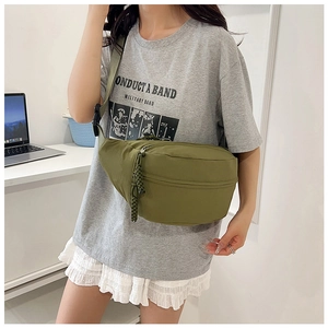 Detailed close-up of olive green nylon chest bag with woven zipper pull and adjustable strap