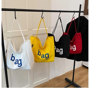 Multiple stylish canvas tote bags with 'bag' lettering on display racks in a bright room