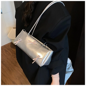 Silver baguette bag with pink ribbon bows on shoulder showing metallic texture details