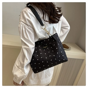 Détail du sac cabas noir à motif nœuds blancs, bandoulière cuir et boucle chaîne dorée