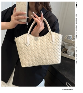 Détail d'un sac cabas tressé crème montrant le motif en losange et l'anse ronde