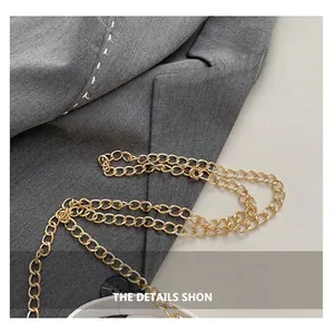 Detail of elegant gold metal chain strap with ring clasp on a grey suit fabric background