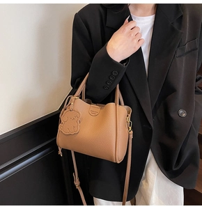 Detail of brown litchi pattern leather tote with gold hardware and puppy charm