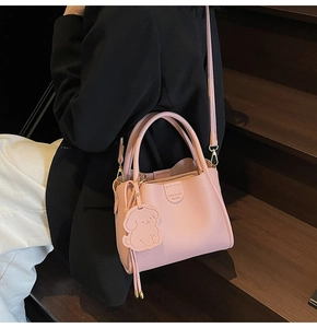 Detailed macro view of pink litchi grain leather texture and metallic logo on bucket bag