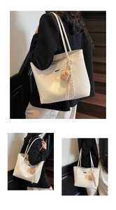 Detail view of woven texture tote bag with silver logo and plush bear charm