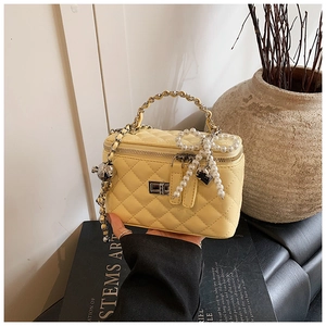 Detail van gele gewatteerde mini-tas met zilveren sluiting en parelmoeren strik hanger