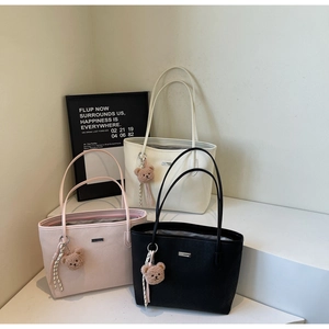 Three minimalist tote bags in cream, pink, and black with cute plush bear charms