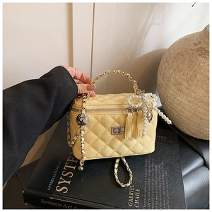 Detail van beige gewatteerde box bag met parelmoeren strikhanger en metalen kettingriem