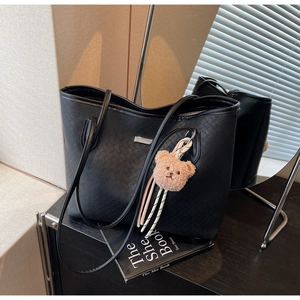 Close-up of black woven texture tote bag with a cute brown plush bear charm