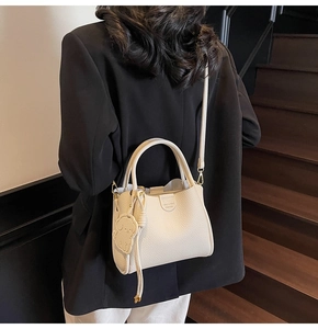 Detailed back view of a minimalist cream bucket bag with dog pendant and leather texture