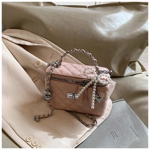 Detail van roze gewatteerde box bag met parelmoer strik en zilveren ketting