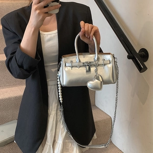 Silver mirror metallic handbag with pearl chain strap and heart charm on a model