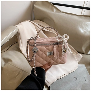 Detail van roze gewatteerde box-tas met zilveren sluiting en parelmoer strik hanger