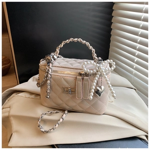 Detail van beige gewatteerde tas met parelstrikn en zilveren ketting schouderriem